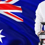 Holding books and graduation cap over Australia flag