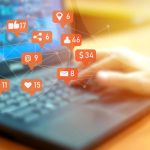 Businessman using laptop with social media notifications on screen
