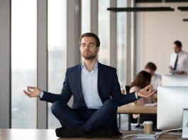 Calm businessman in suit meditating on office desk for Spiritual Awareness