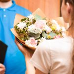 courier hands bouquet to young woman, flower delivery