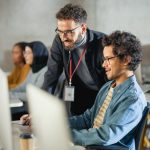 Teacher Giving Lesson to Diverse Multiethnic Group of Female and Male Students in College Room, Teaching New Academic Skills on a Computer in Germany