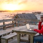 A man working on a laptop outdoors at the beach. A man working on a laptop outdoors at the beach.