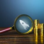 Coins stack with magnifying glass for start up