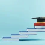 wooden people sign and graduation cap for MBA on book stairs