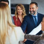 A diverse business team smiling and joining hands in a show of unity, care and teamwork.