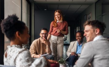 A group of motivated professionals sharing ideas, laughter, engagement, collaboration and collaboration in a bright office space, reflecting teamwork and creativity in a business environment.