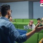 Male Teacher Giving a Lecture to a Diverse Multiethnic Group of Female and Male Students in Modern College Room