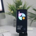 a cell phone sitting on top of a stand on a desk for buying bitcoin