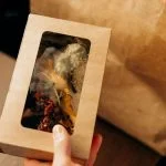 Food in a Carboard Box and a Paper Bag on a Wooden Surface